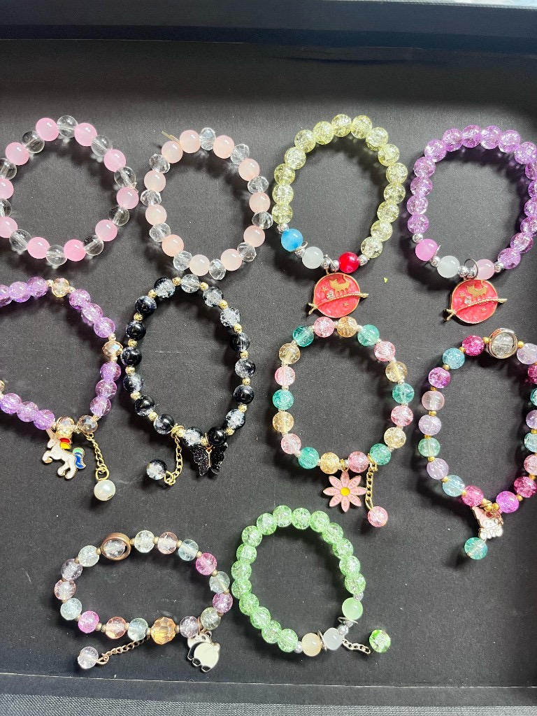 Crackle bead bracelets with charms on a dark background